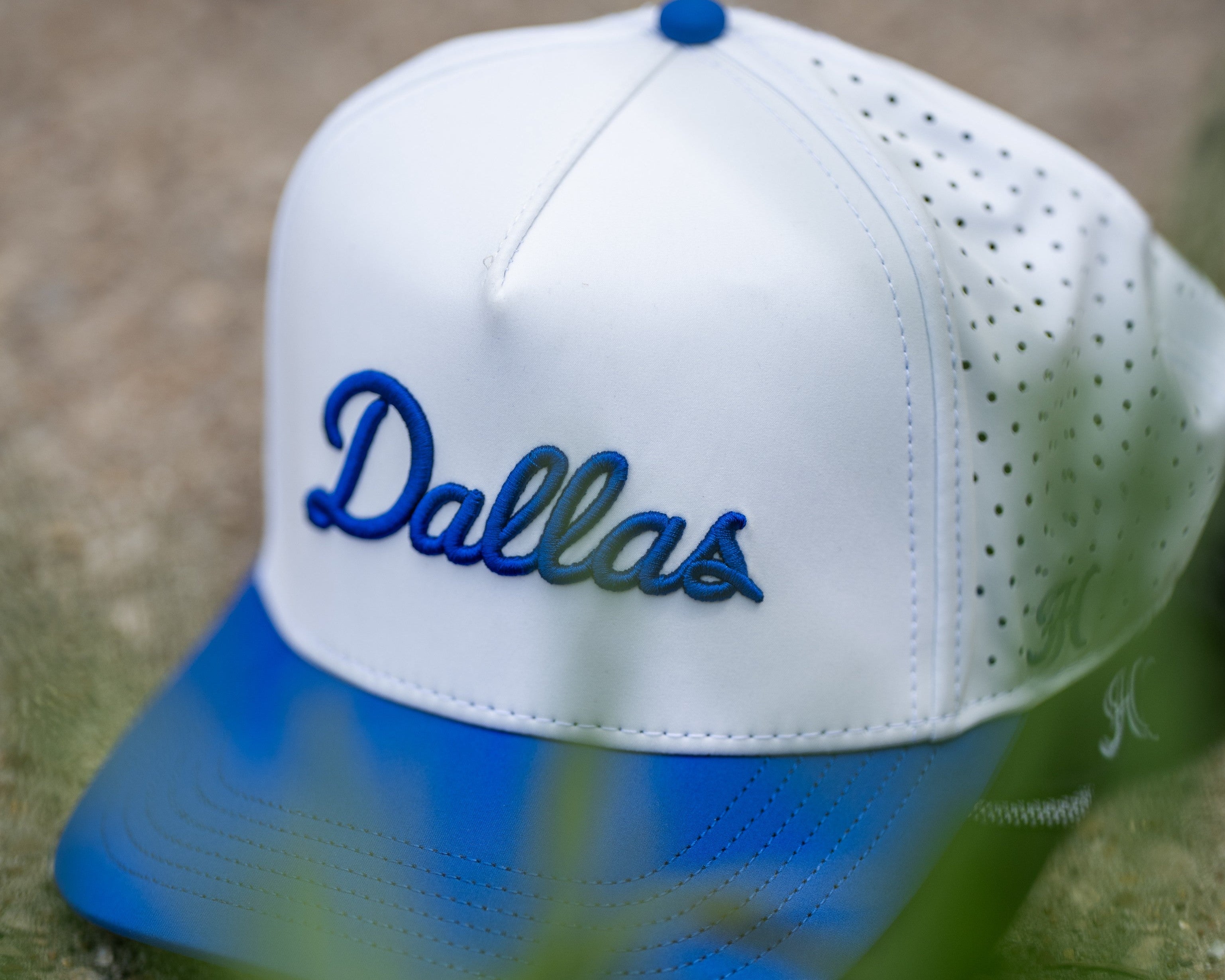 White and blue cap with 'Dallas' text on a grassy background