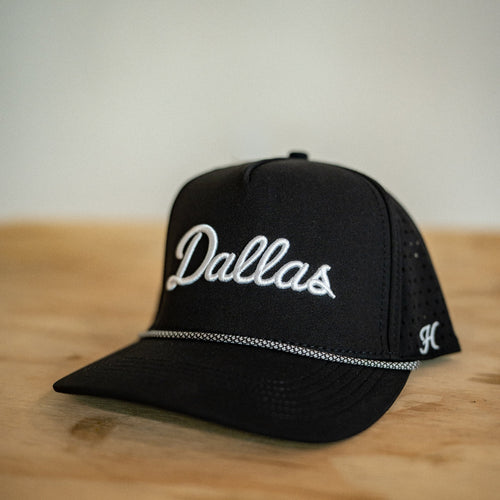 Black cap with 'Dallas' text on a wooden surface