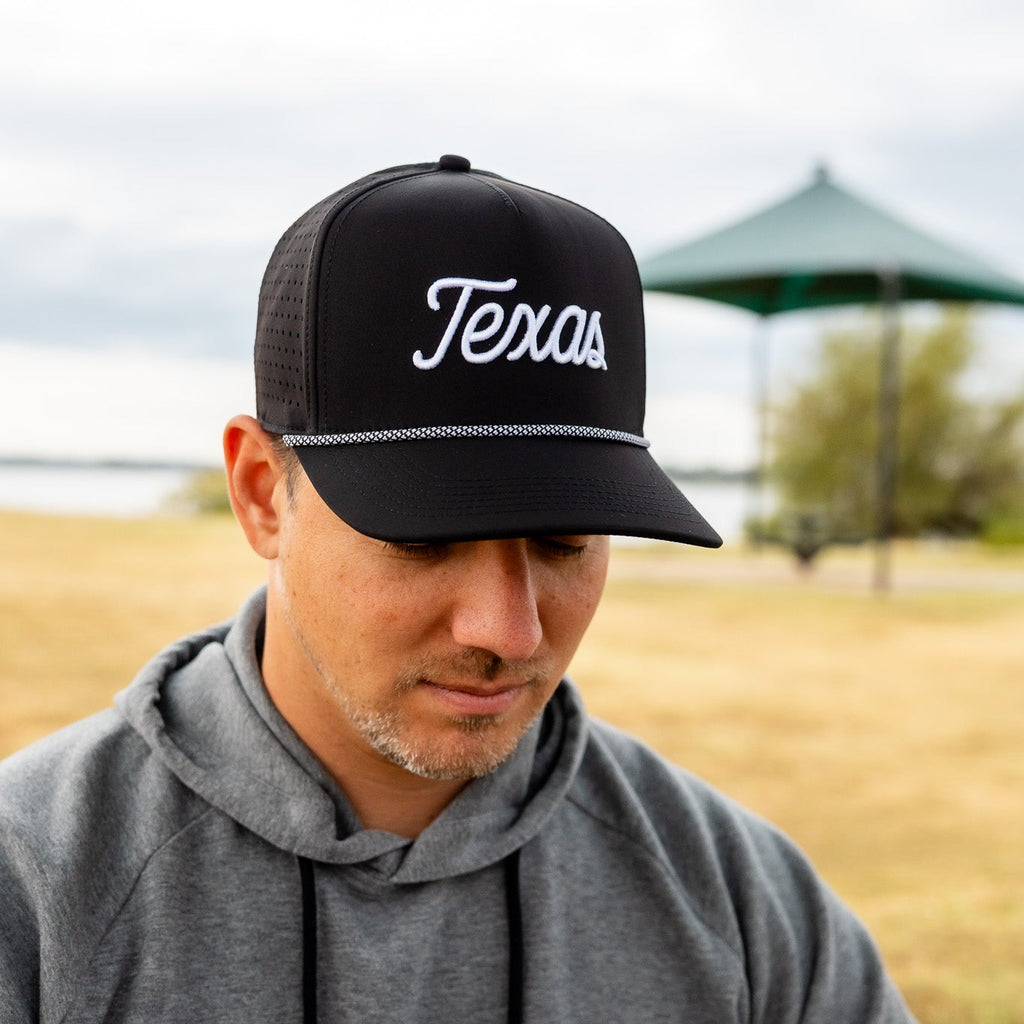 Man wearing a black cap with 'Texas' on it in an outdoor setting