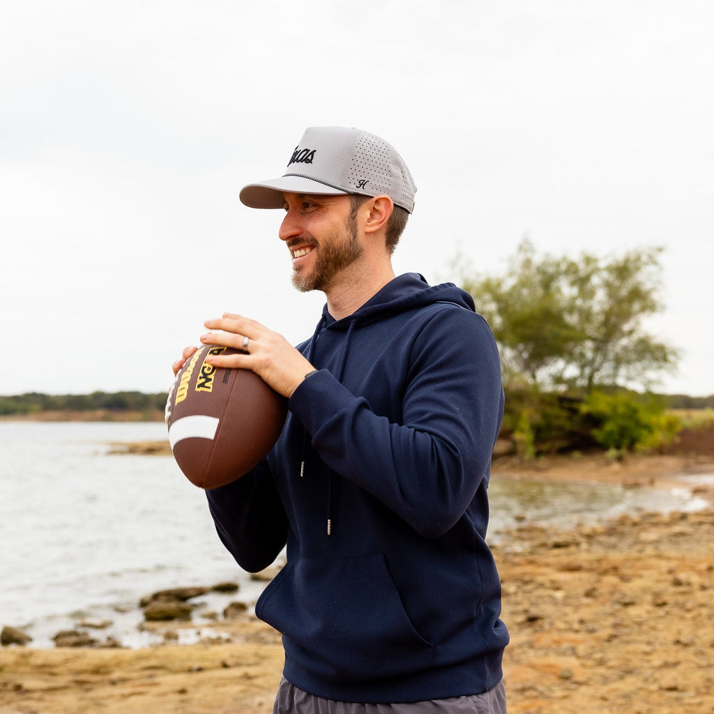 Man holding a football by a body of water