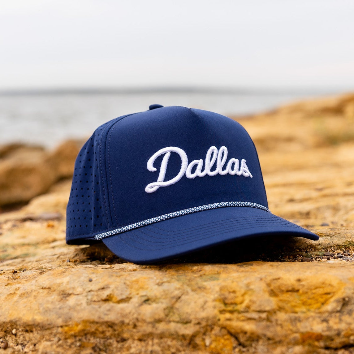 Blue cap with 'Dallas' text on a rocky surface