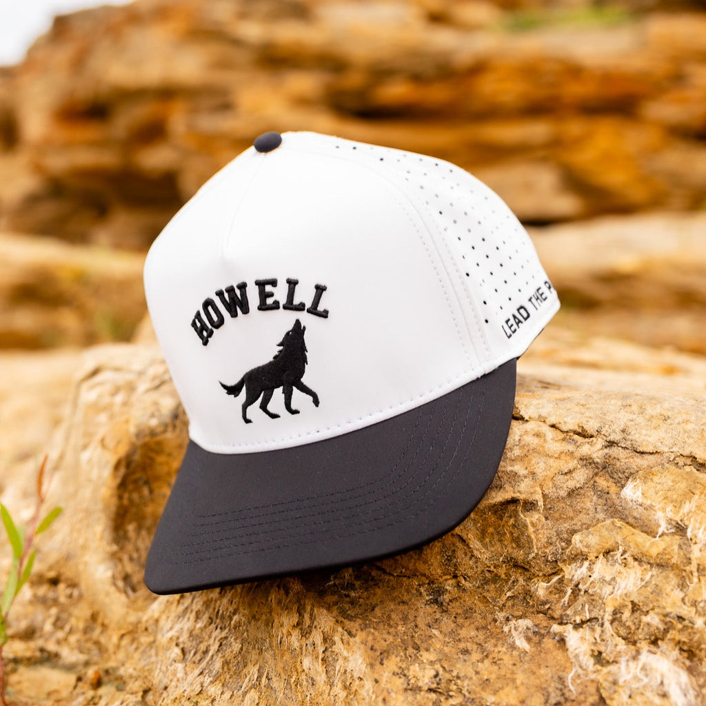 White and black cap with 'HOWELL' and wolf design on a rock background