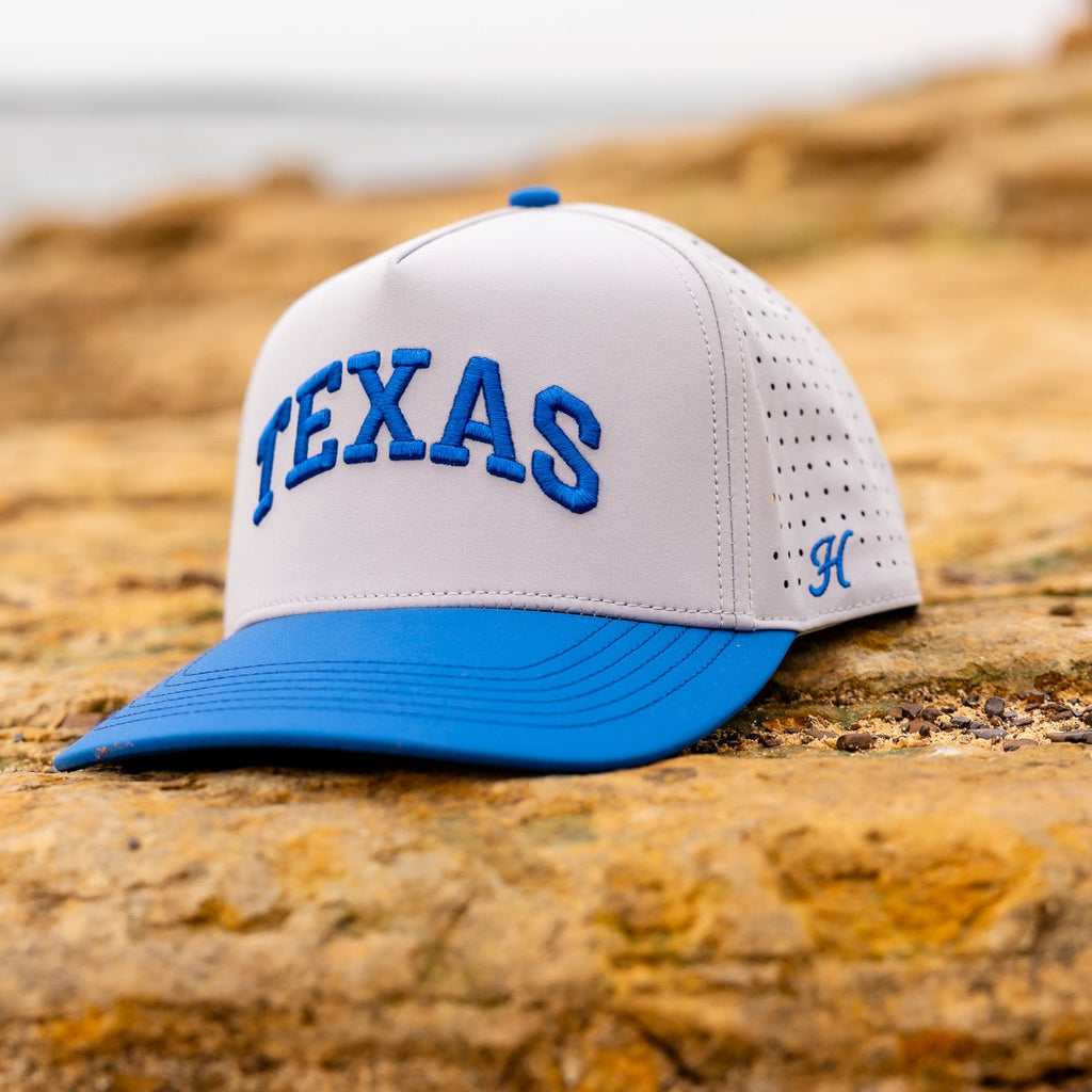 White and blue cap with 'TEXAS' text on a rocky surface