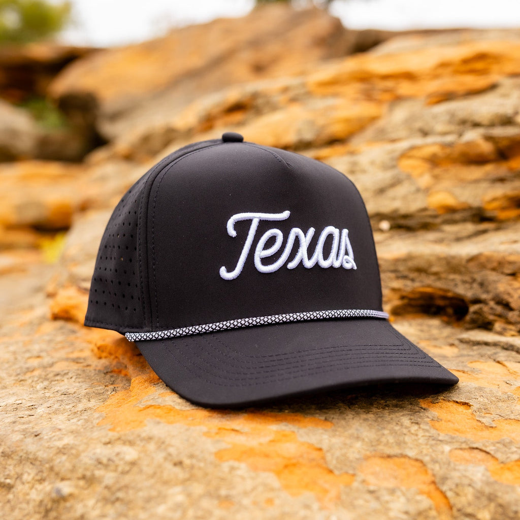 Black cap with 'Texas' text on a textured rock surface