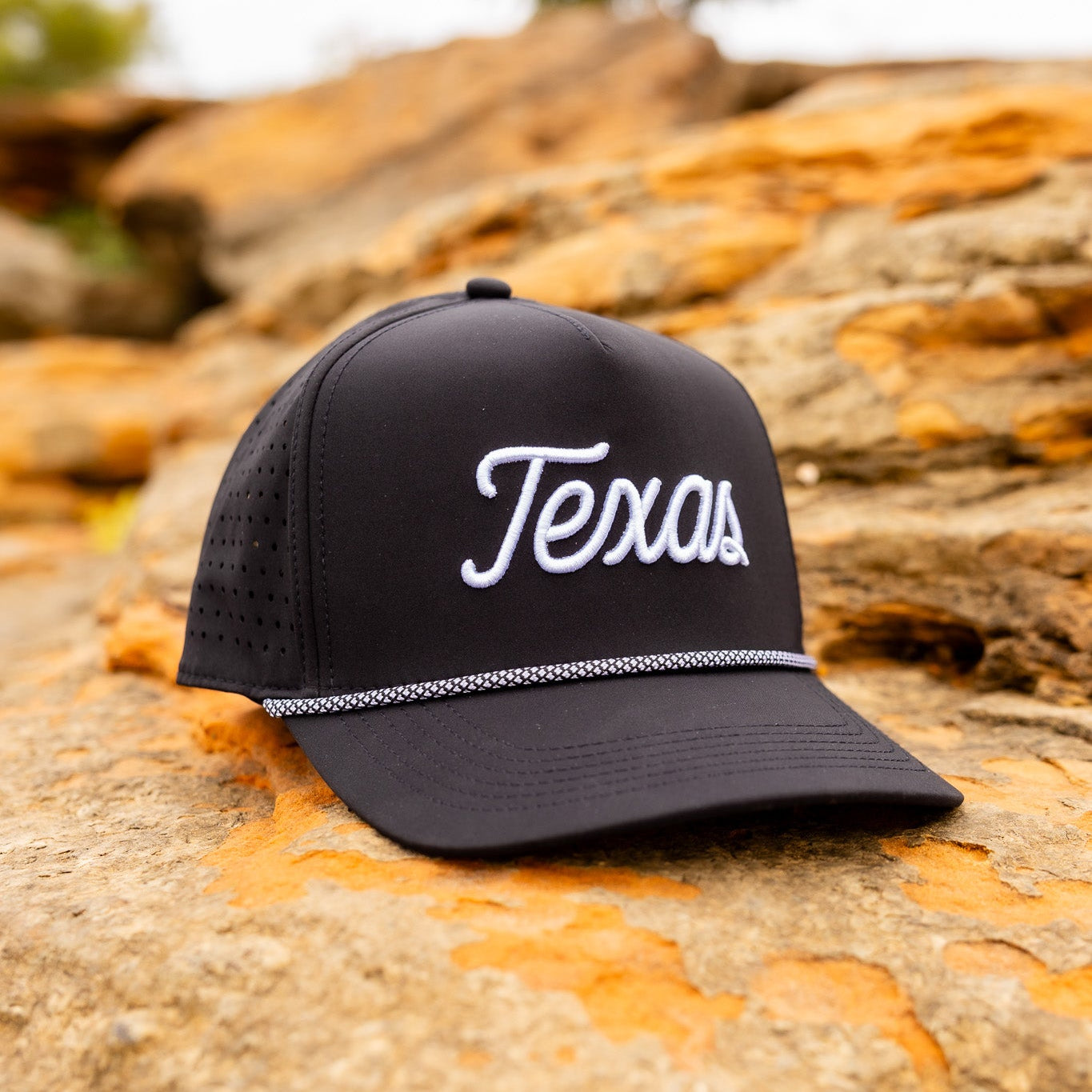 Black cap with 'Texas' text on a textured rock surface